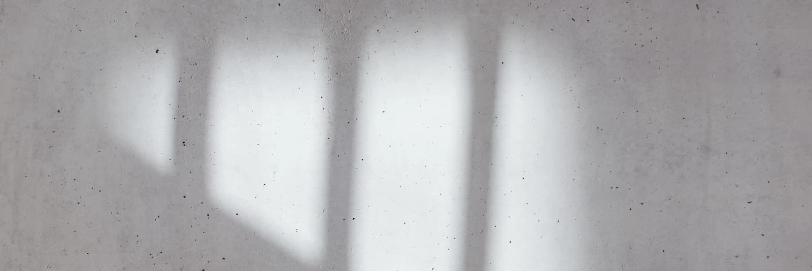 Pale window light on a bare concrete wall