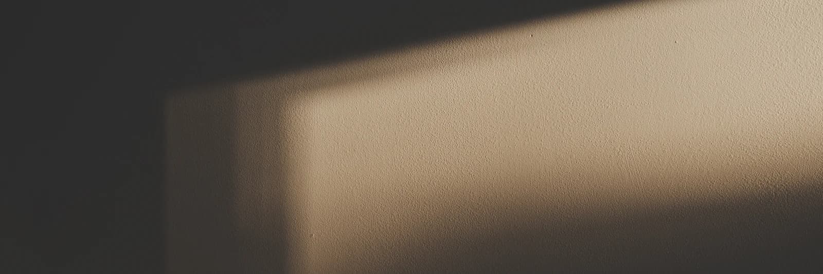 Soft daylight from a window falling across a plain wall